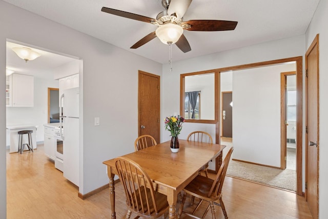 dining room featuring light wood-style floors, baseboards, and ceiling fan