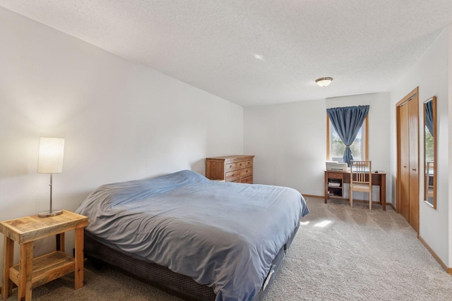 bedroom featuring baseboards, light carpet, and a textured ceiling