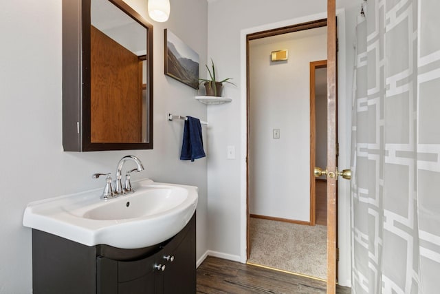 bathroom with baseboards, wood finished floors, and vanity