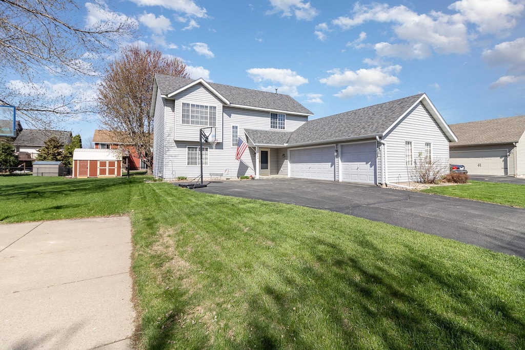 traditional home with an attached garage, a front lawn, and driveway