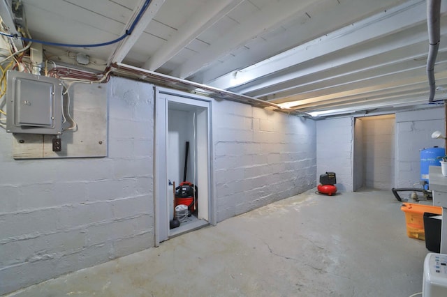 unfinished below grade area with electric panel and a water pressure tank