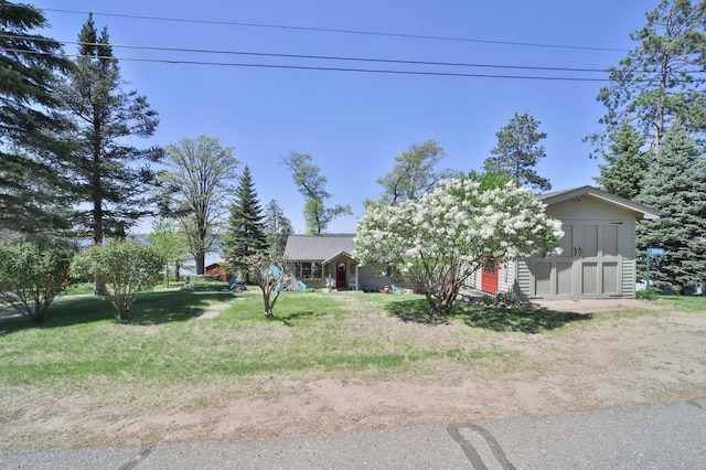 obstructed view of property featuring a storage unit, a front lawn, and an outbuilding