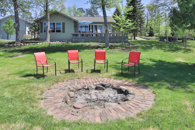view of green lawn featuring an outdoor fire pit and a wooden deck