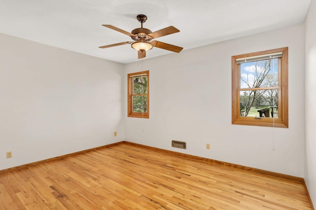 spare room featuring baseboards, a ceiling fan, and light wood-style floors