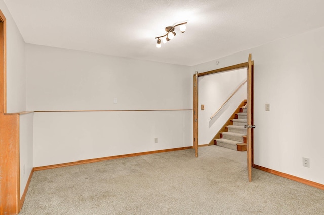 unfurnished room featuring light carpet, stairs, and baseboards