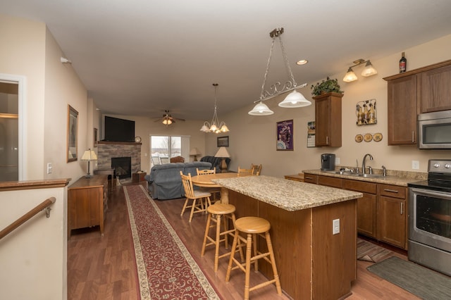 4129 Jarmann Ln, Shakopee, MN 55379 - kitchen with dark wood finished floors, a kitchen breakfast bar, stainless steel appliances, a sink, and a kitchen island