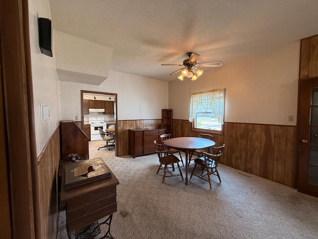 128 Munsterman St, Appleton, MN 56208 - carpeted dining space with a wainscoted wall, a textured ceiling, visible vents, ceiling fan, and wooden walls