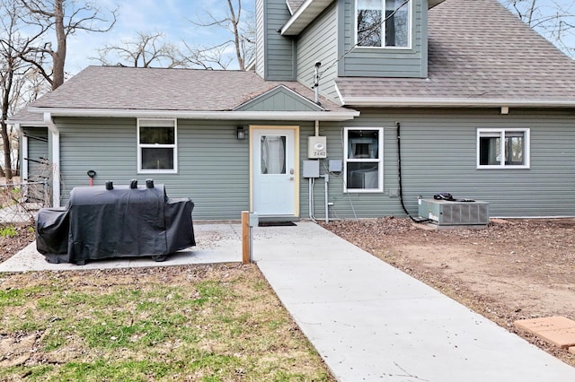 exterior space with a shingled roof and cooling unit