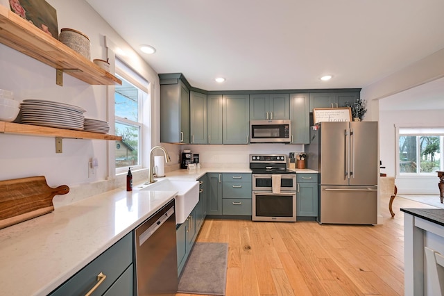 kitchen with light wood finished floors, a sink, open shelves, stainless steel appliances, and recessed lighting