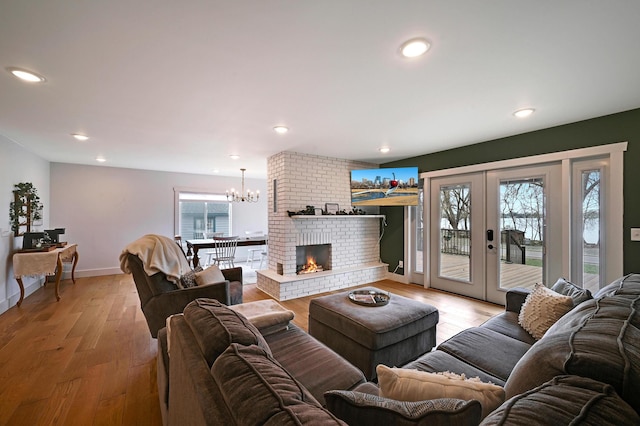 living area with baseboards, a notable chandelier, light wood finished floors, and recessed lighting
