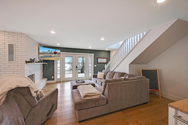 living room featuring french doors, recessed lighting, light wood-style flooring, a brick fireplace, and baseboards