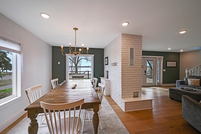 dining space with a chandelier, stairs, a healthy amount of sunlight, and wood finished floors