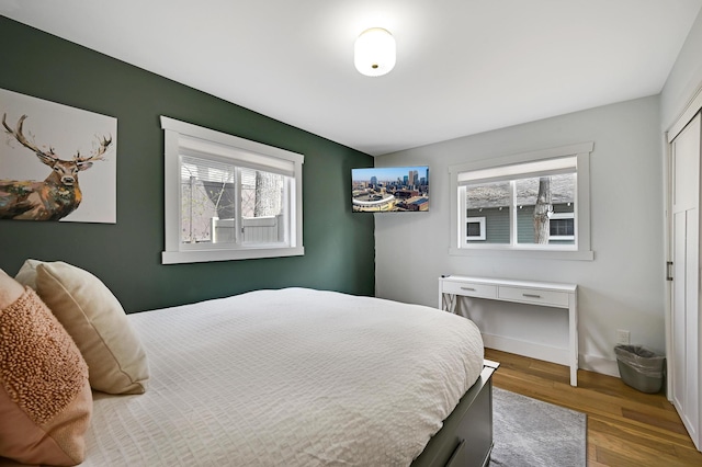 bedroom featuring baseboards, multiple windows, and wood finished floors