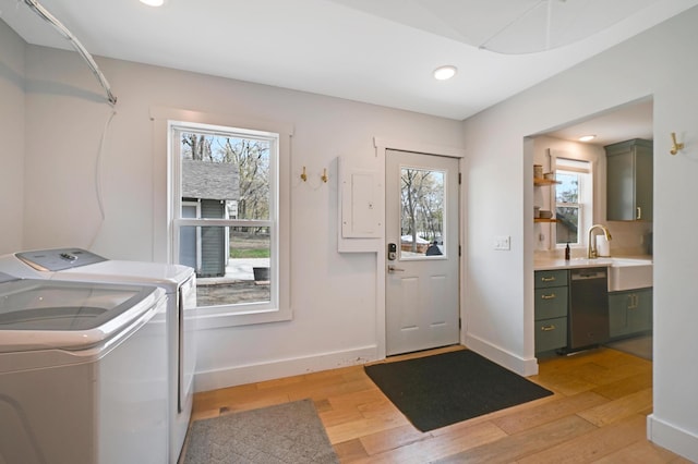 clothes washing area with separate washer and dryer, a wealth of natural light, baseboards, and light wood-type flooring