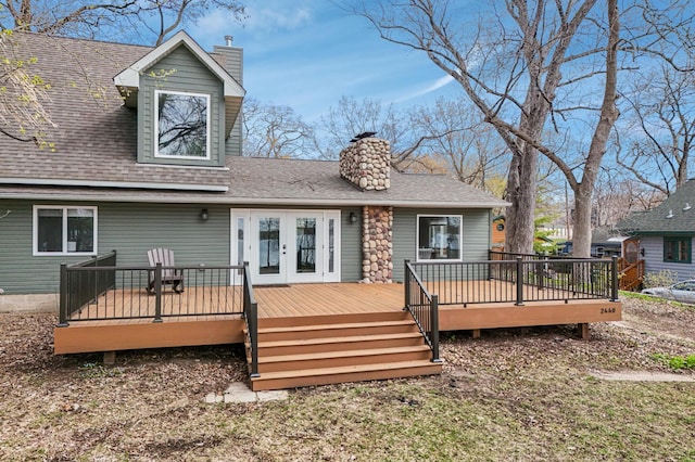 rear view of house with a chimney, a deck, roof with shingles, and french doors