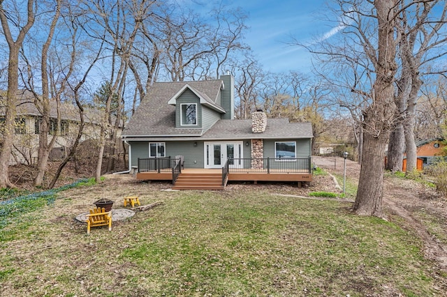 back of property with french doors, a yard, a wooden deck, a chimney, and an outdoor fire pit