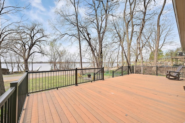 wooden terrace with a water view and a yard