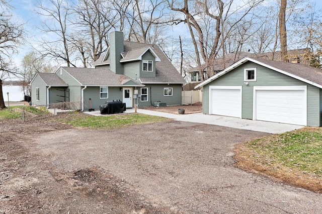 view of front of house with a chimney, an outbuilding, a detached garage, central air condition unit, and roof with shingles