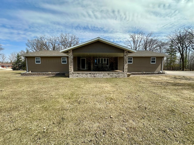 rear view of house with a yard, roof with shingles, and covered porch