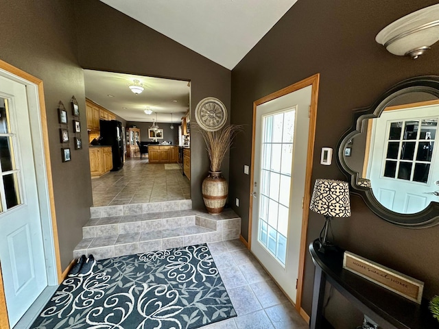 doorway with lofted ceiling, light tile patterned flooring, and baseboards