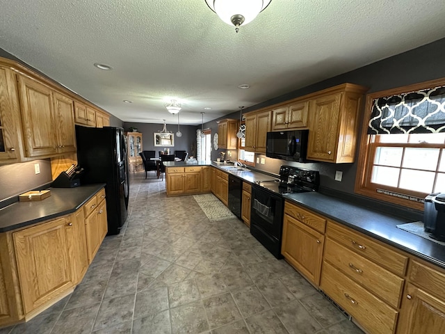 kitchen featuring black appliances, a peninsula, dark countertops, and plenty of natural light