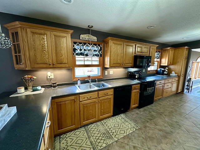 kitchen featuring brown cabinetry, black appliances, a sink, and a textured ceiling