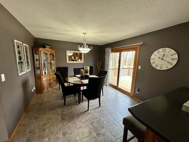 dining area featuring light tile patterned flooring, a chandelier, a textured ceiling, and baseboards