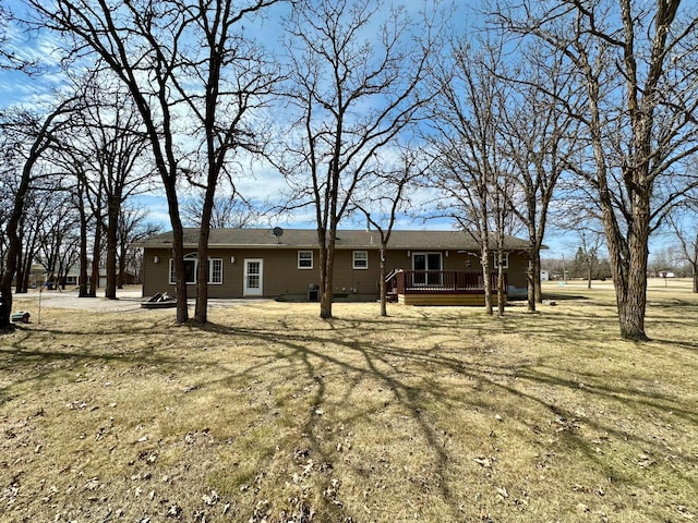 back of property featuring a wooden deck and a yard