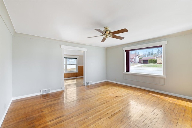 unfurnished room with visible vents, light wood-type flooring, a ceiling fan, and baseboards