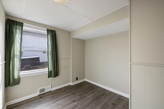 spare room with visible vents, a drop ceiling, wood finished floors, and baseboards