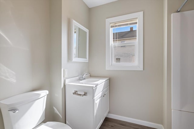 bathroom featuring toilet, wood finished floors, vanity, and baseboards