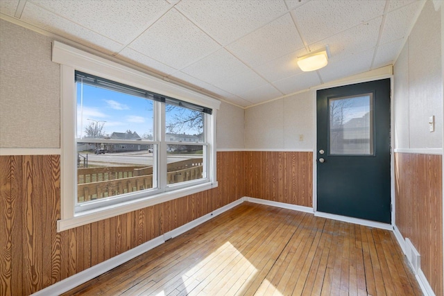 interior space with lofted ceiling, wood walls, hardwood / wood-style floors, a wainscoted wall, and baseboards