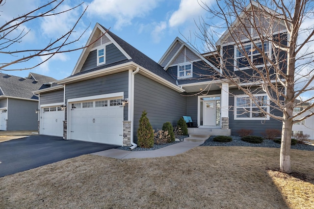 craftsman inspired home featuring an attached garage, aphalt driveway, stone siding, and a front lawn