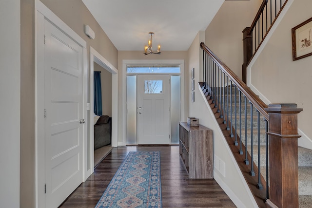 entryway featuring stairway, dark wood-style floors, and an inviting chandelier