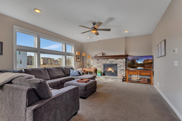 carpeted living area featuring a ceiling fan, baseboards, recessed lighting, and a stone fireplace