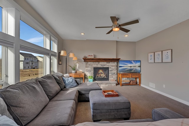 living area featuring a ceiling fan, a stone fireplace, baseboards, carpet flooring, and visible vents