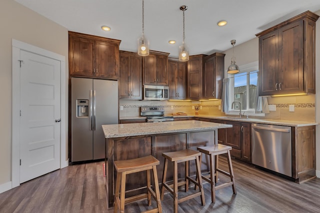 kitchen featuring a center island, a sink, stainless steel appliances, dark wood finished floors, and recessed lighting
