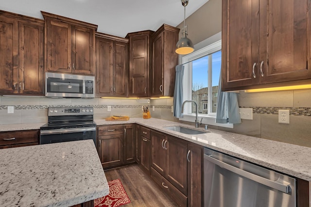 kitchen featuring tasteful backsplash, a sink, appliances with stainless steel finishes, light stone countertops, and dark wood-style floors