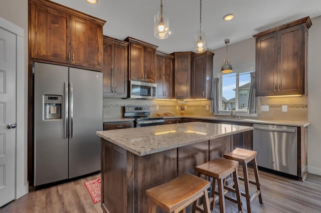 kitchen featuring decorative backsplash, a sink, light wood-style floors, and appliances with stainless steel finishes