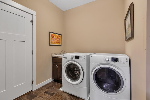 clothes washing area with a sink, baseboards, separate washer and dryer, stone finish flooring, and cabinet space