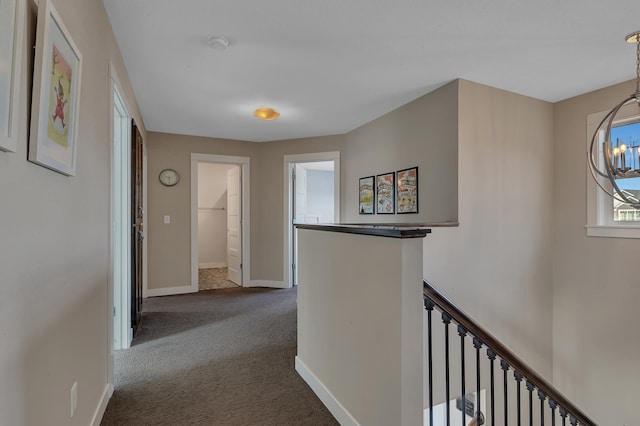 corridor featuring an inviting chandelier, carpet flooring, baseboards, and an upstairs landing