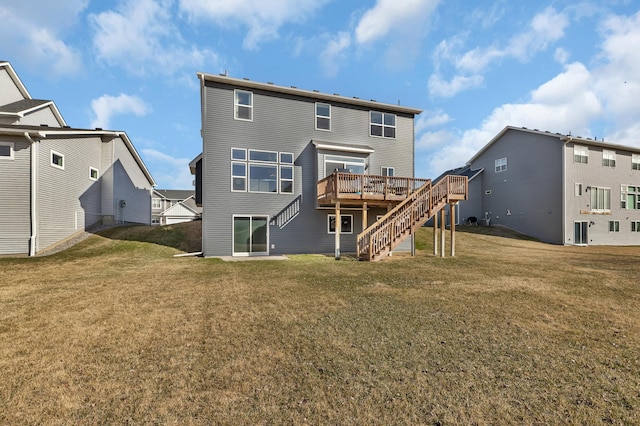 rear view of property featuring a lawn, a wooden deck, and stairs