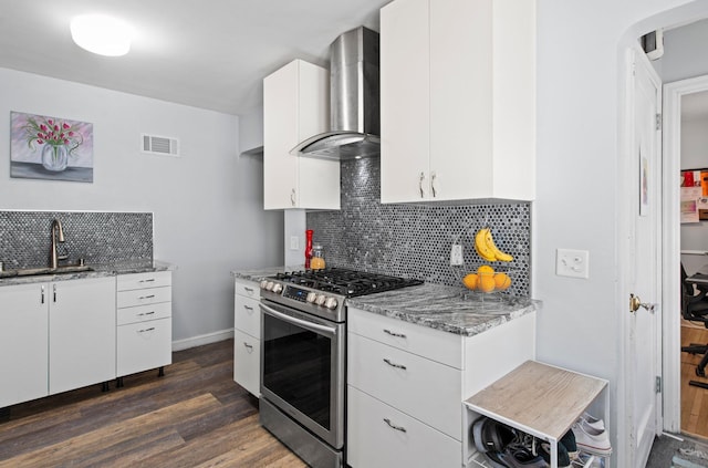kitchen featuring wall chimney range hood, dark wood-style flooring, a sink, stainless steel range with gas cooktop, and visible vents