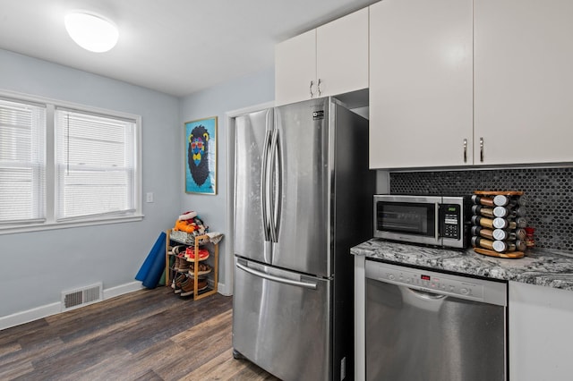 kitchen with dark wood-style flooring, visible vents, appliances with stainless steel finishes, light stone countertops, and white cabinets