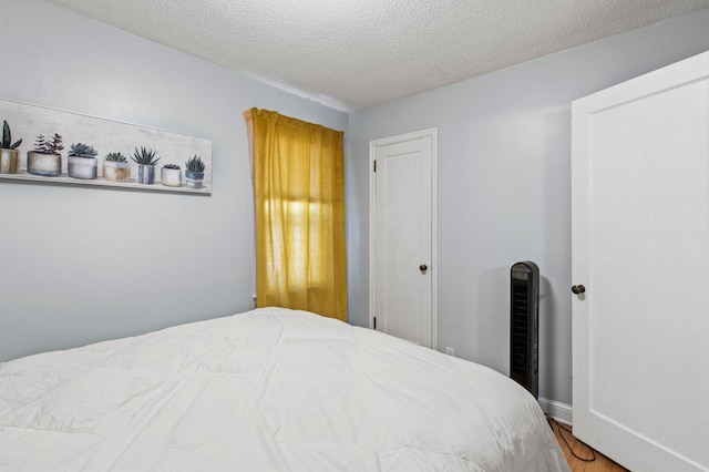 bedroom with a textured ceiling, baseboards, a closet, and wood finished floors