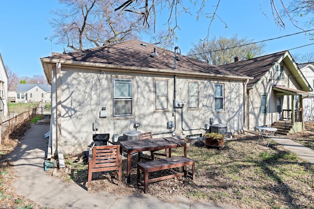 rear view of property with central air condition unit, fence, and stucco siding