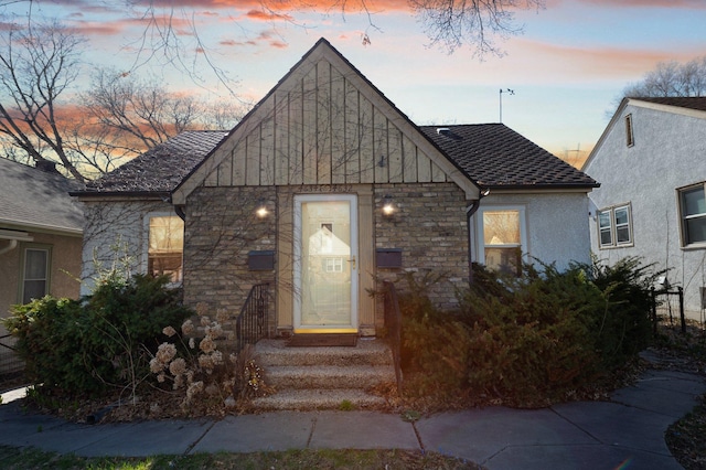view of front of property with roof with shingles and stone siding