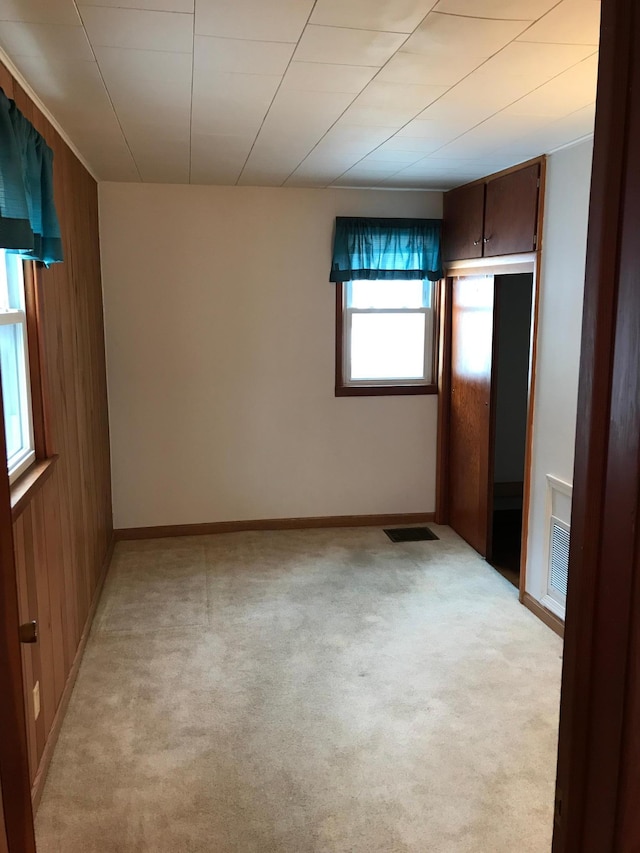 1509 5th St, Mankato, MN 56001 - unfurnished bedroom featuring wood walls, baseboards, visible vents, and light colored carpet
