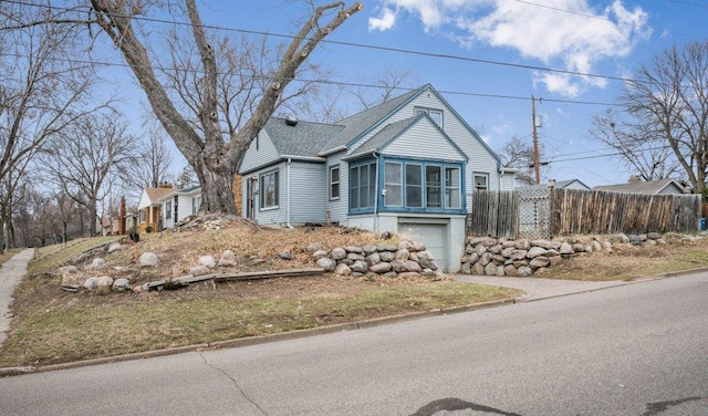 view of front facade featuring fence, driveway, a shingled roof, and a garage