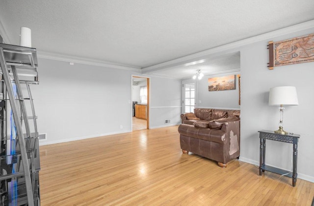 living area featuring light wood-style floors, visible vents, crown molding, and baseboards